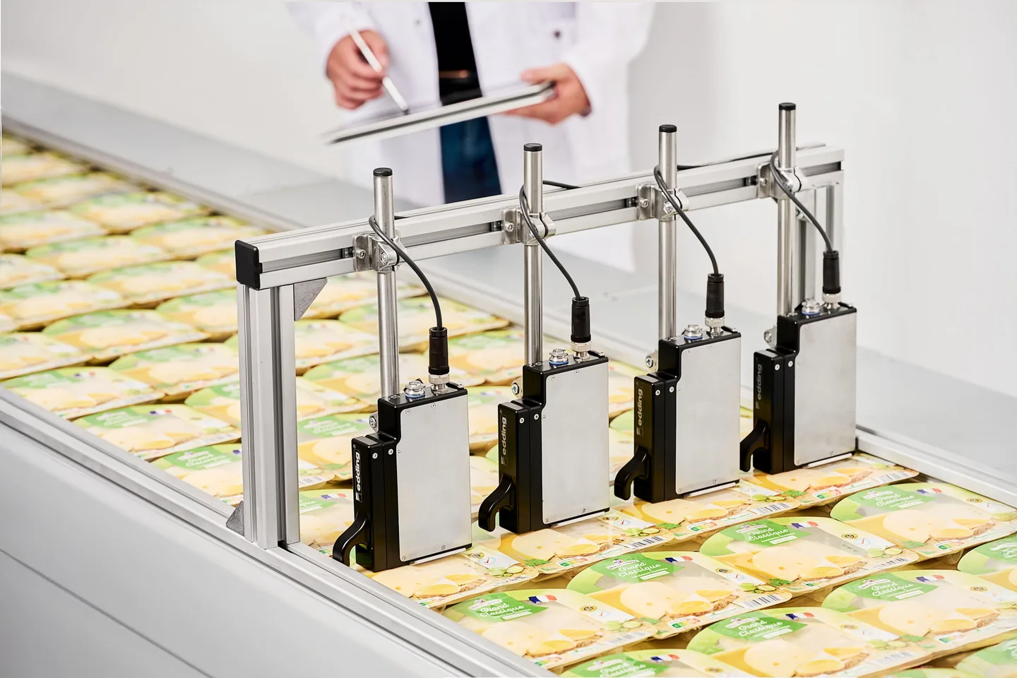 Four print heads integrated into a cheese production line for marking best-before dates.
