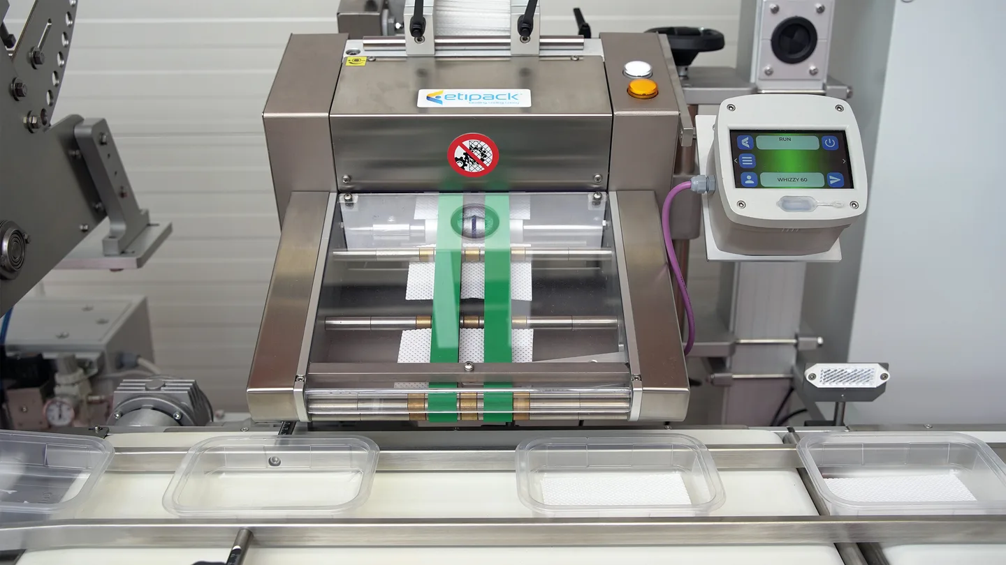 Stepper motor friction feeder dispensing soaker pads into meat trays